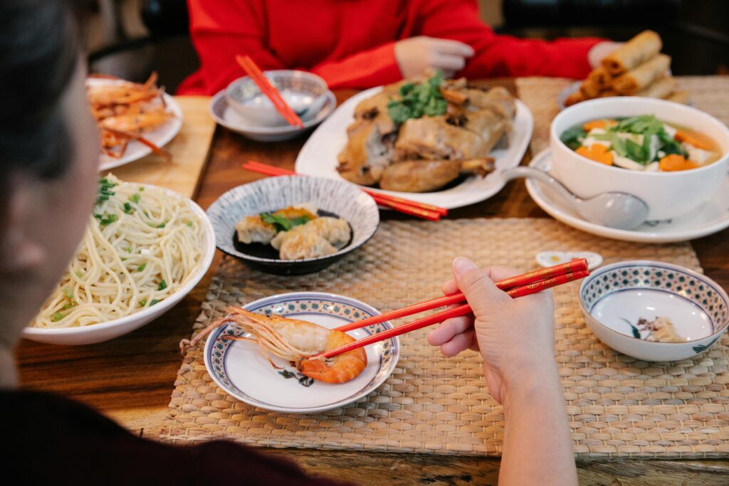A family enjoying a traditional Lunar New Year feast with various dishes at home.