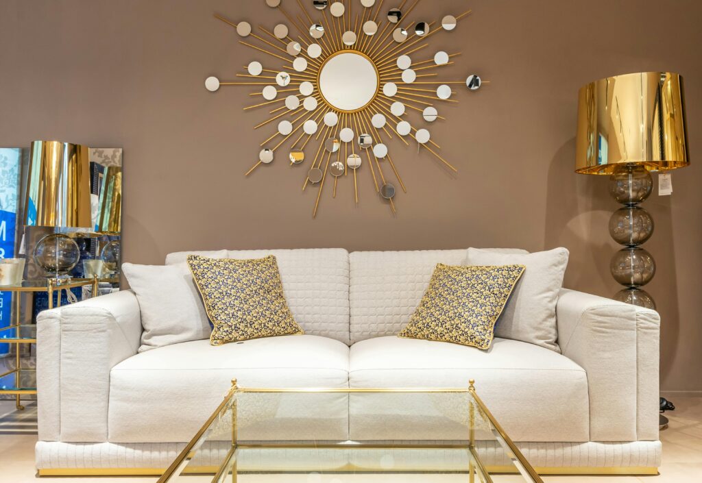 A contemporary living room featuring a stylish sofa with gold decor elements and a sunburst wall mirror.