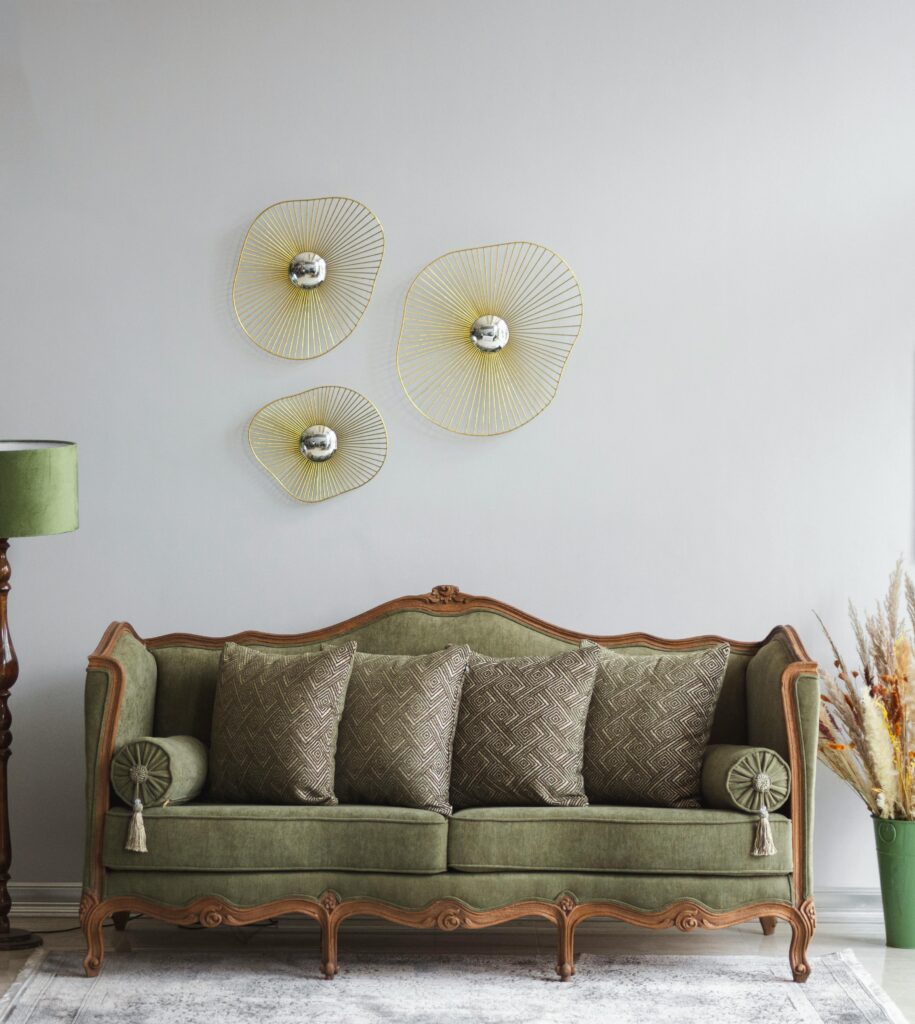 Vintage green sofa in a stylish living room with artistic wall decor and a floor lamp.