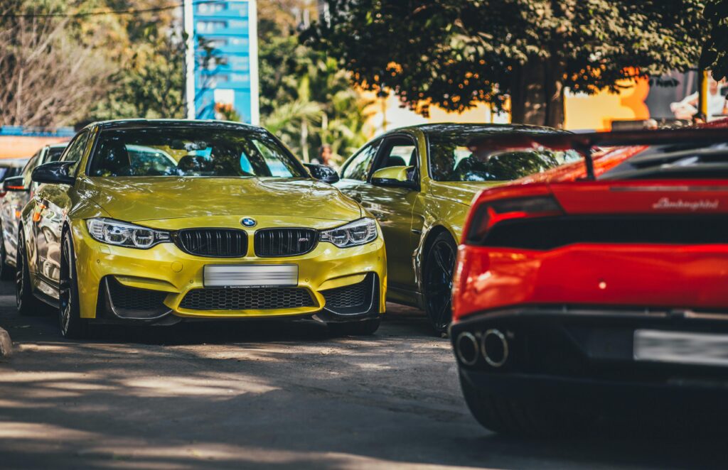 Vibrant BMW and supercar parked on sunny New Delhi road.