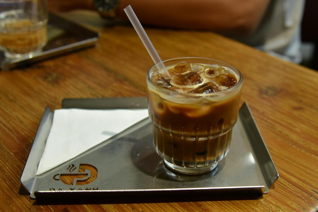 A delicious glass of iced coffee with a straw on a metal tray with napkins, perfect for a summer drink.
