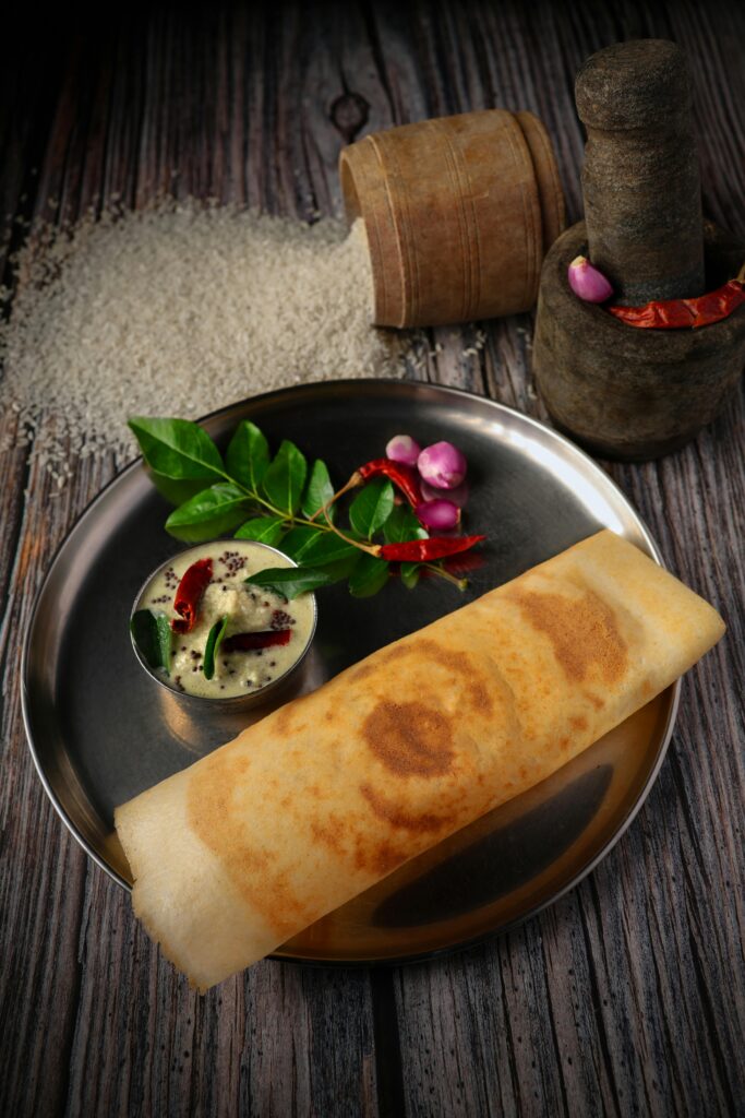 A traditional South Indian dosa served with coconut chutney on a rustic wooden table.
