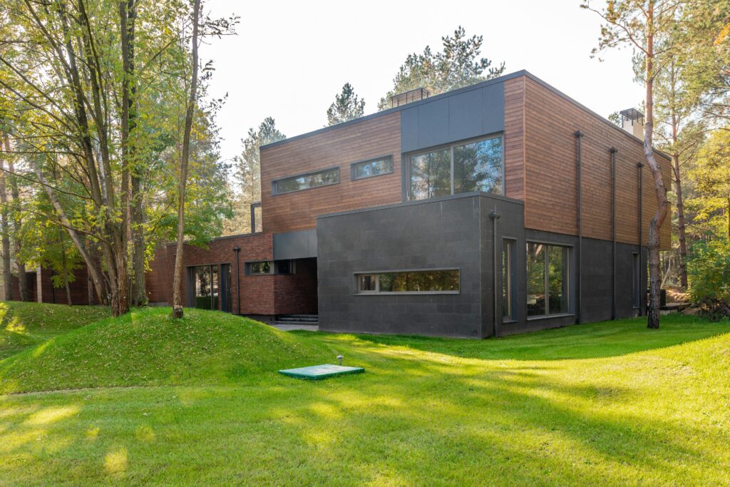 A contemporary wooden house with large glass windows set in a lush forest.