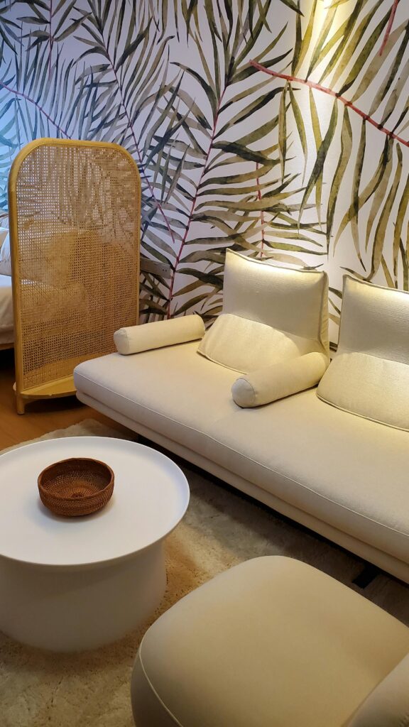 Stylish interior with sofa and leafy wallpaper, featuring elegant design elements like a round table and separator.