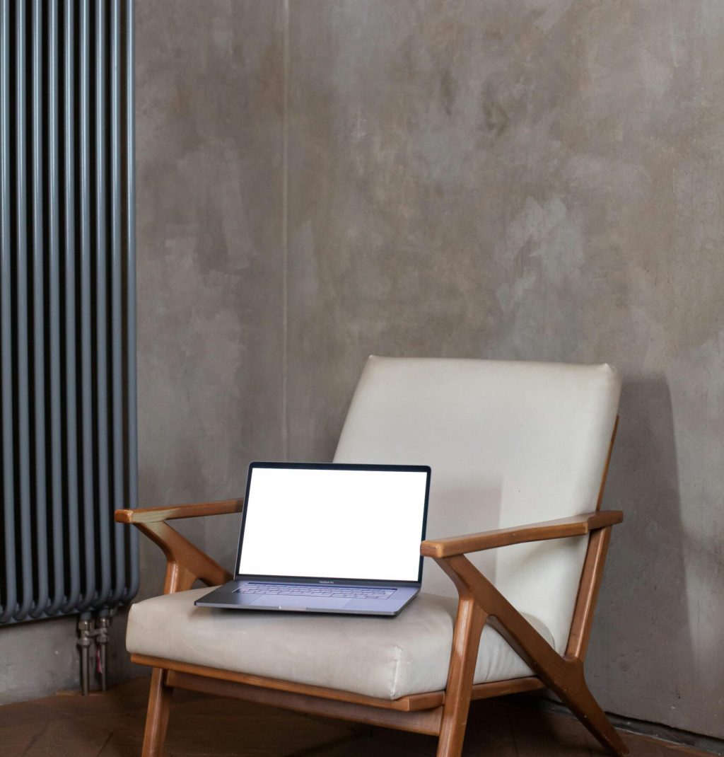 A minimalist armchair setup featuring a laptop with a blank screen for creative displays.